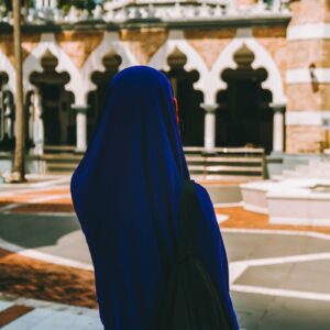A woman in a blue hijab is looking at a building