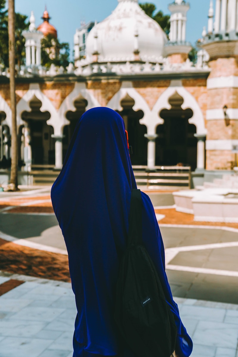 A woman in a blue hijab is looking at a building